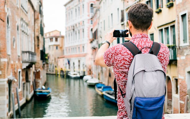 Traveler photographing a canal in Venice during a photo walking tour.
