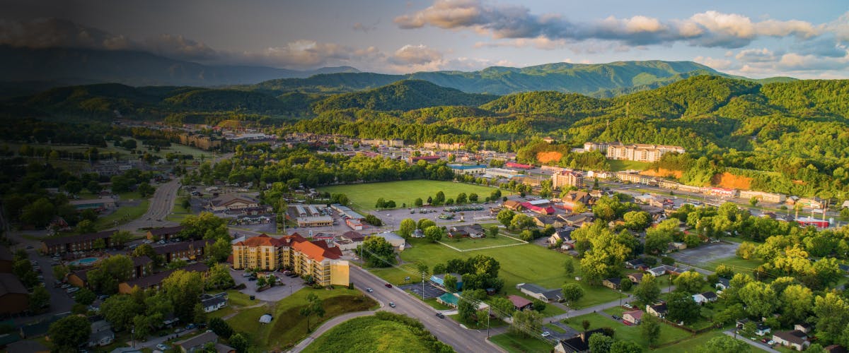 Aerial view of Pigeon Forge, United States, with lush green hills and cityscape.