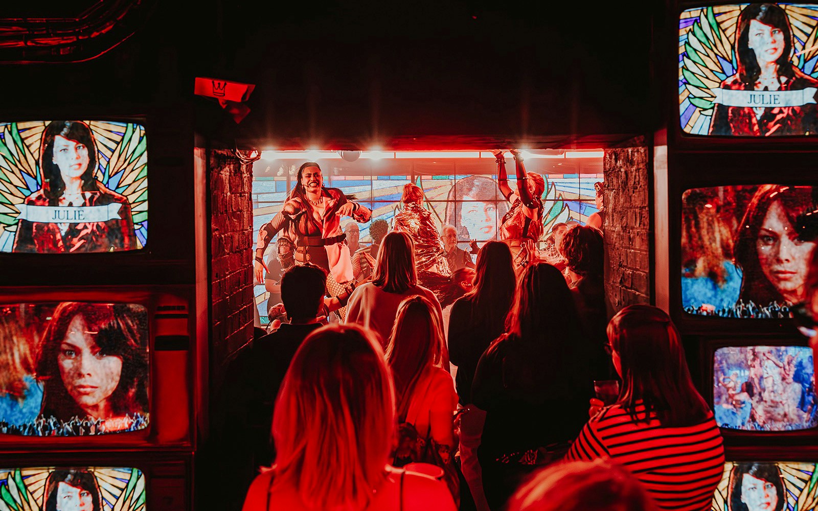 Crowd enjoying a live performance at Oscar at the Crown, surrounded by vibrant screens.