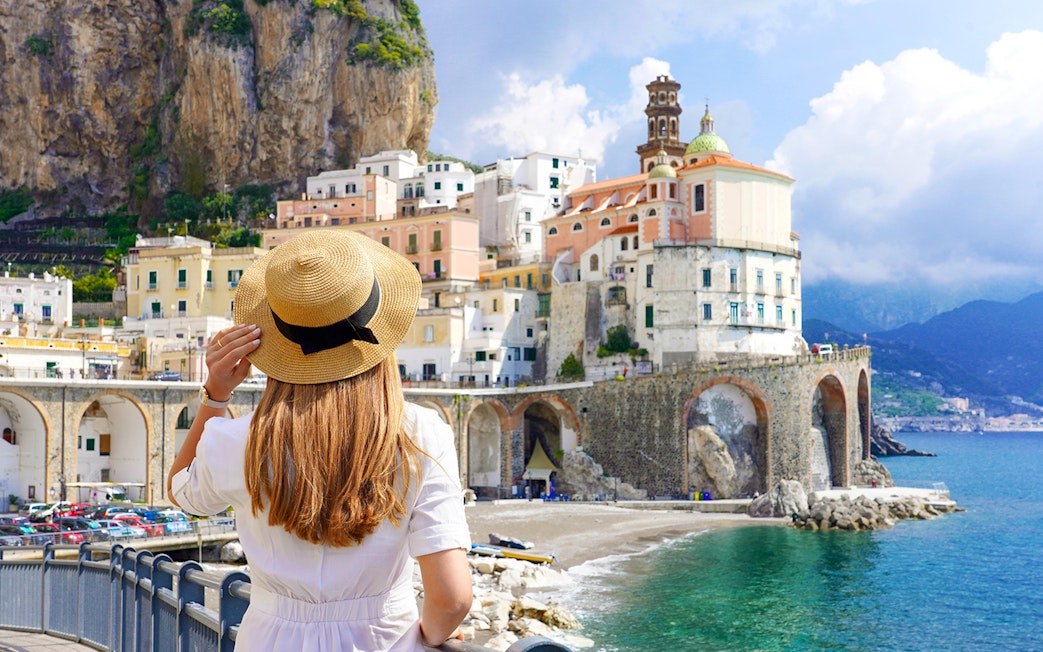 Young girl admiring Amalfi Coast view with colorful cliffside buildings.