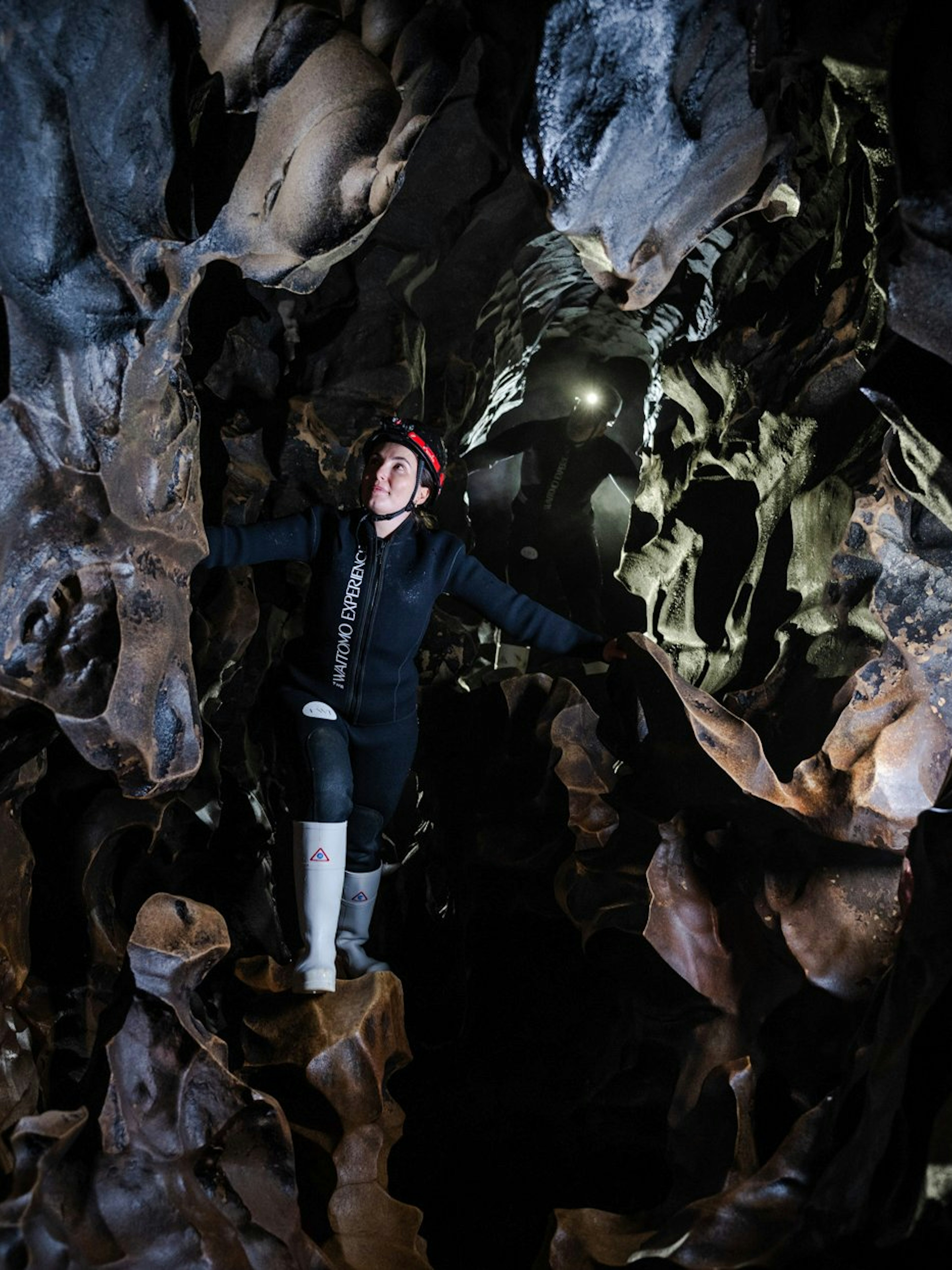 Person exploring Okohua Glowworm Cave in Waitomo, surrounded by unique rock formations.