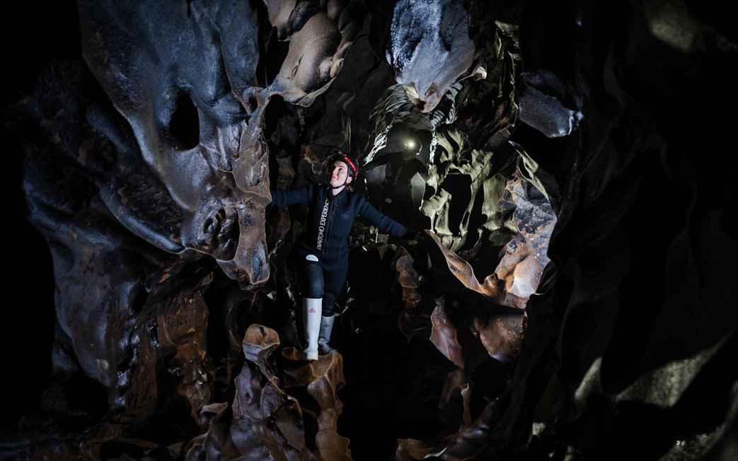 Person exploring Okohua Glowworm Cave in Waitomo, surrounded by unique rock formations.
