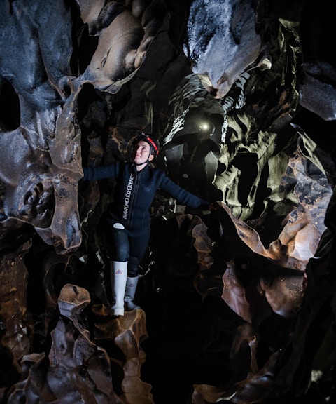 Person exploring Okohua Glowworm Cave in Waitomo, surrounded by unique rock formations.