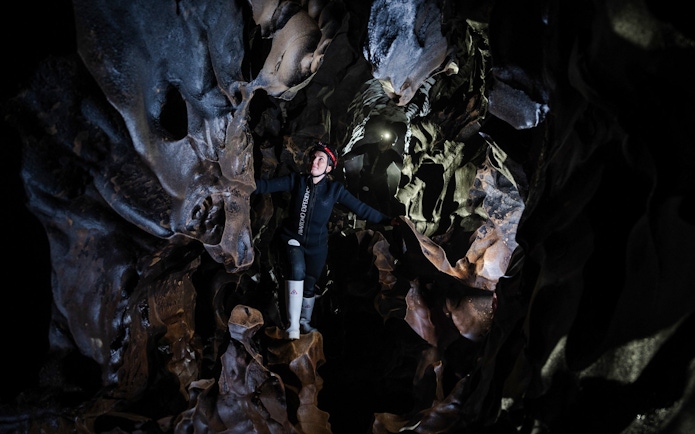 Person exploring Okohua Glowworm Cave in Waitomo, surrounded by unique rock formations.