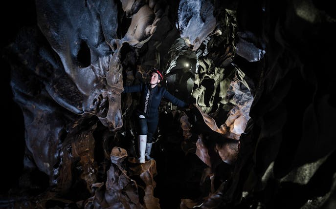Person exploring Okohua Glowworm Cave in Waitomo, surrounded by unique rock formations.