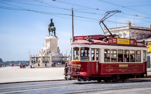 Lisbon tram passing by Praça do Comércio with equestrian statue in view.