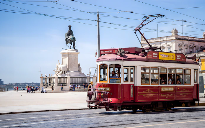 Lisbon tram passing by Praça do Comércio with equestrian statue in view.