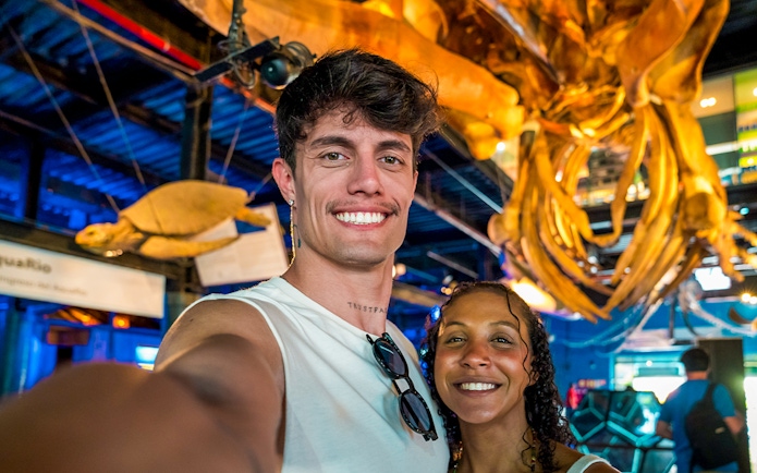 Tourists smiling in front of large octopus structure at AquaRio aquarium in Rio de Janeiro.