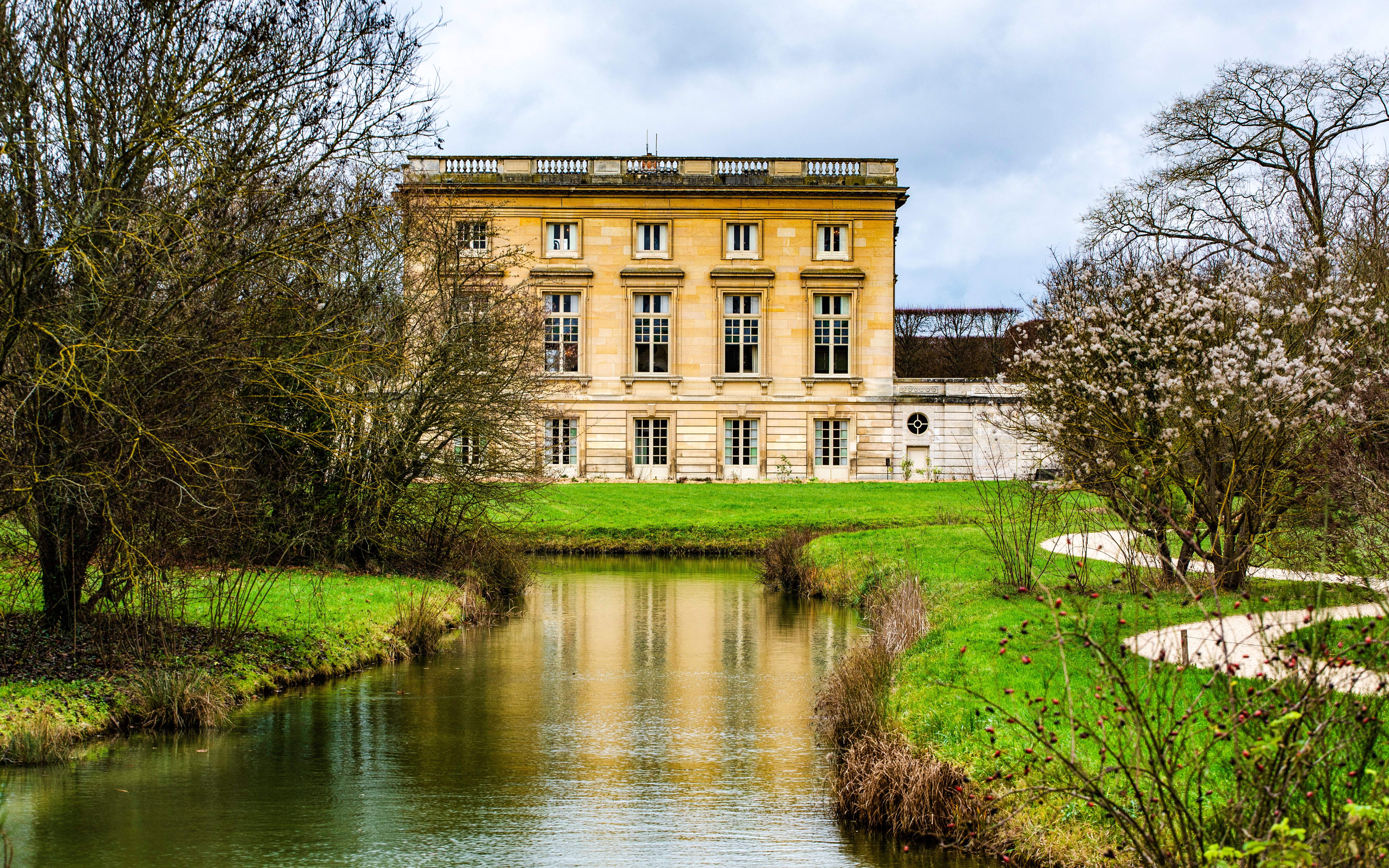 Grand Trianon building with surrounding gardens and canal in Versailles, France.