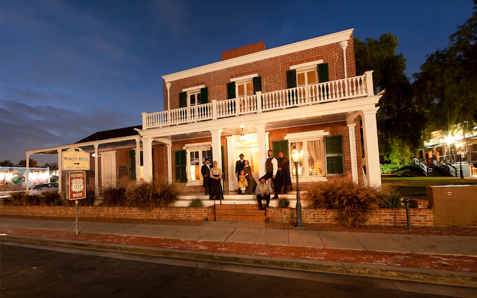 Whaley House at night with actors in period costumes, San Diego Ghosts & Gravestones Tour.