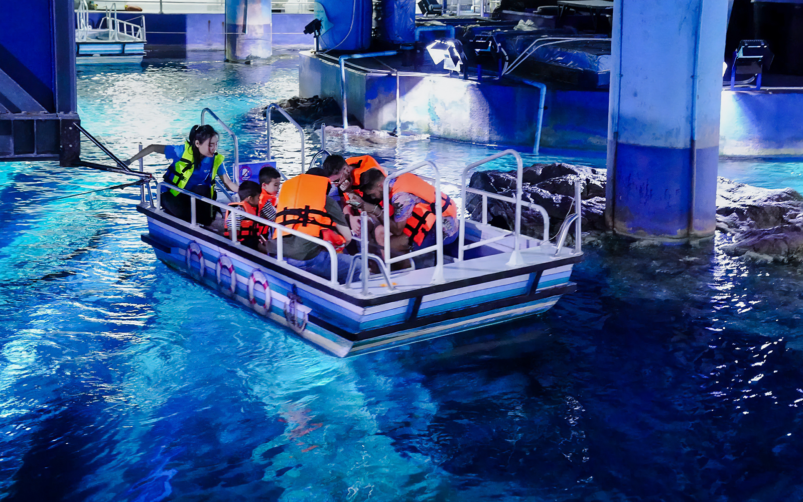 Visitors on a glass bottom boat tour at Sea Life Bangkok, viewing marine life.