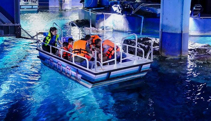 Visitors on a glass bottom boat tour at Sea Life Bangkok, viewing marine life.