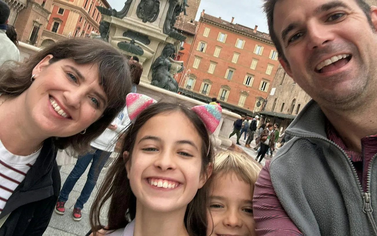 Family enjoying Bologna's Neptune Fountain during city exploration game.