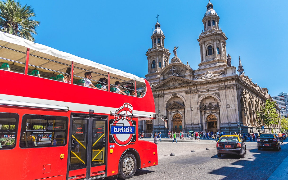 Red double-decker bus in front of Santiago Metropolitan Cathedral, Chile.
