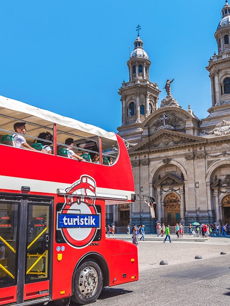 Red double-decker bus in front of Santiago Metropolitan Cathedral, Chile.
