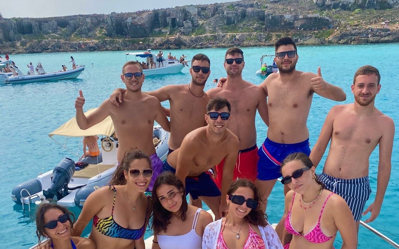 Group enjoying Favignana and Levanzo boat tour from Marsala, with clear blue waters and rocky coastline.