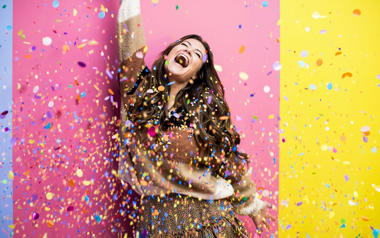 Person celebrating with colorful confetti at WONDR Experience.