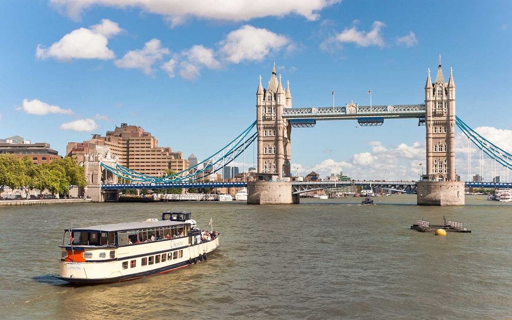 River cruise boat near Tower Bridge, London, on a sunny day.