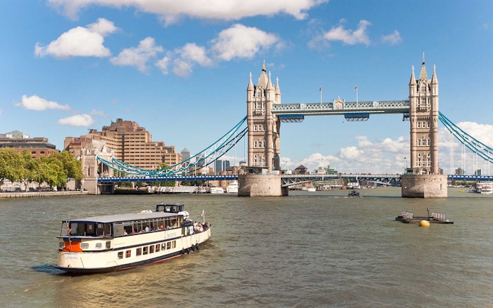 River cruise boat near Tower Bridge, London, on a sunny day.