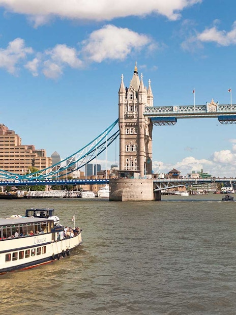 River cruise boat near Tower Bridge, London, on a sunny day.