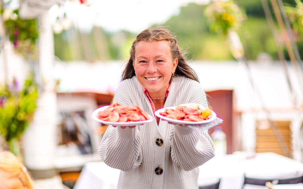 Staff presenting seafood plates on Oslofjord dinner cruise.