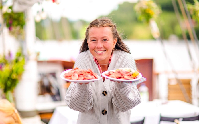 Staff presenting seafood plates on Oslofjord dinner cruise.