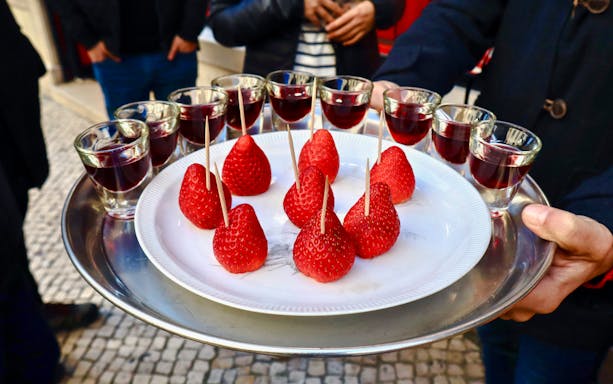 Strawberries and glasses of wine on a tray during Lisbon food tour.