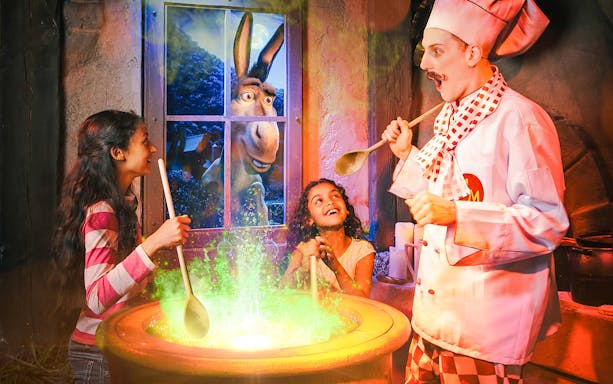 Guests enjoying a cooking experience at Shrek's Adventure in London with Donkey visible through the window.