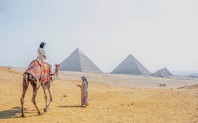 Woman riding a camel near the pyramids at Giza Necropolis, Cairo day trip from Hurghada.