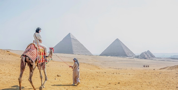 Woman riding a camel near the pyramids at Giza Necropolis, Cairo day trip from Hurghada.