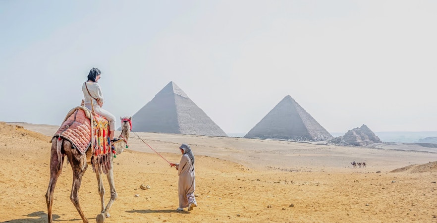 Woman riding a camel near the pyramids at Giza Necropolis, Cairo day trip from Hurghada.