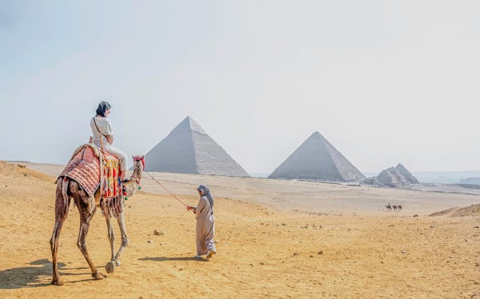 Woman riding a camel near the pyramids at Giza Necropolis, Cairo day trip from Hurghada.