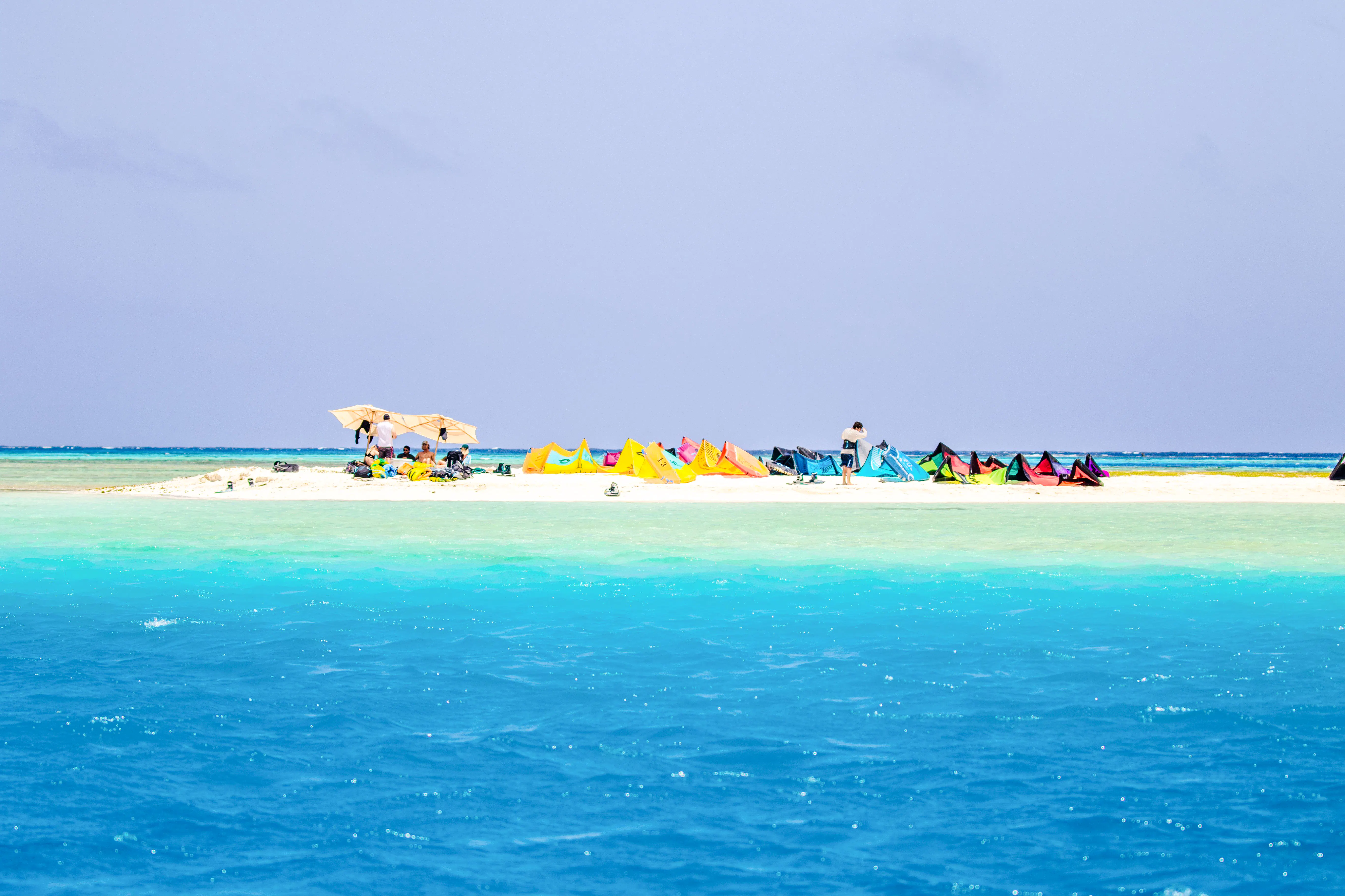 Snorkeling gear and tourists on Mnemba Island Atoll beach, Zanzibar.