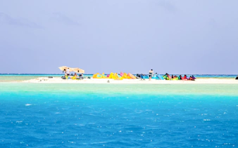 Snorkeling gear and tourists on Mnemba Island Atoll beach, Zanzibar.