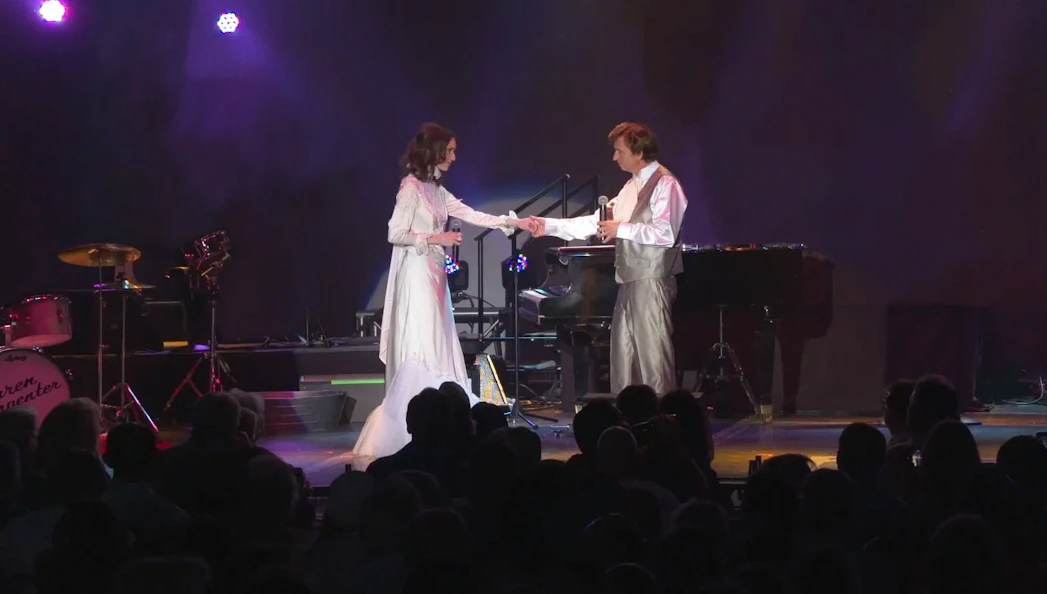 Performers on stage during Carpenters Legacy show with piano and drum set in background.