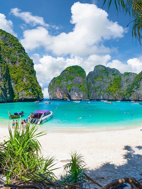 Maya Bay beach with boats and tourists, surrounded by limestone cliffs, Phuket, Thailand.