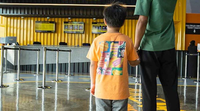 Father and child at Adrenark Theme Park entrance, pointing at the ticket counter.