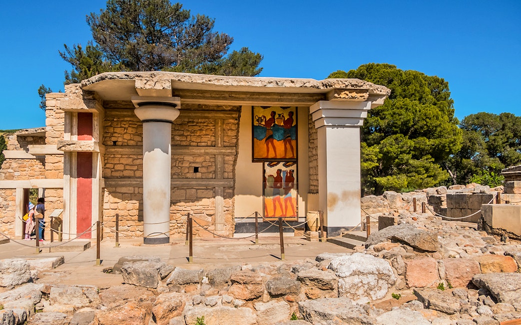 Knossos Palace frescoes and ruins in Crete, Greece, with visitors exploring the site.