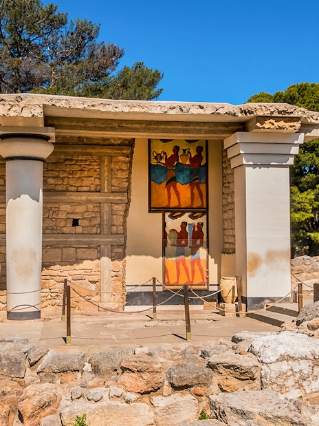 Knossos Palace frescoes and ruins in Crete, Greece, with visitors exploring the site.
