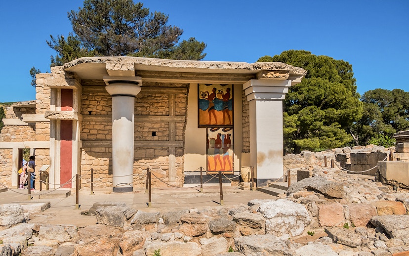 Knossos Palace frescoes and ruins in Crete, Greece, with visitors exploring the site.