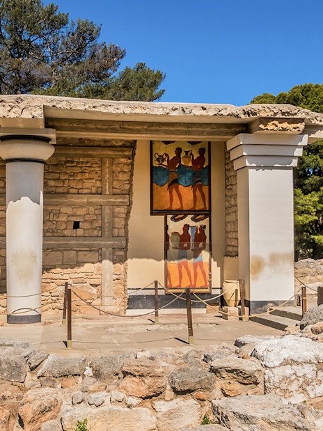 Knossos Palace frescoes and ruins in Crete, Greece, with visitors exploring the site.