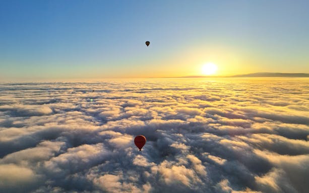 Hot air balloons above clouds at sunrise, Marrakech.