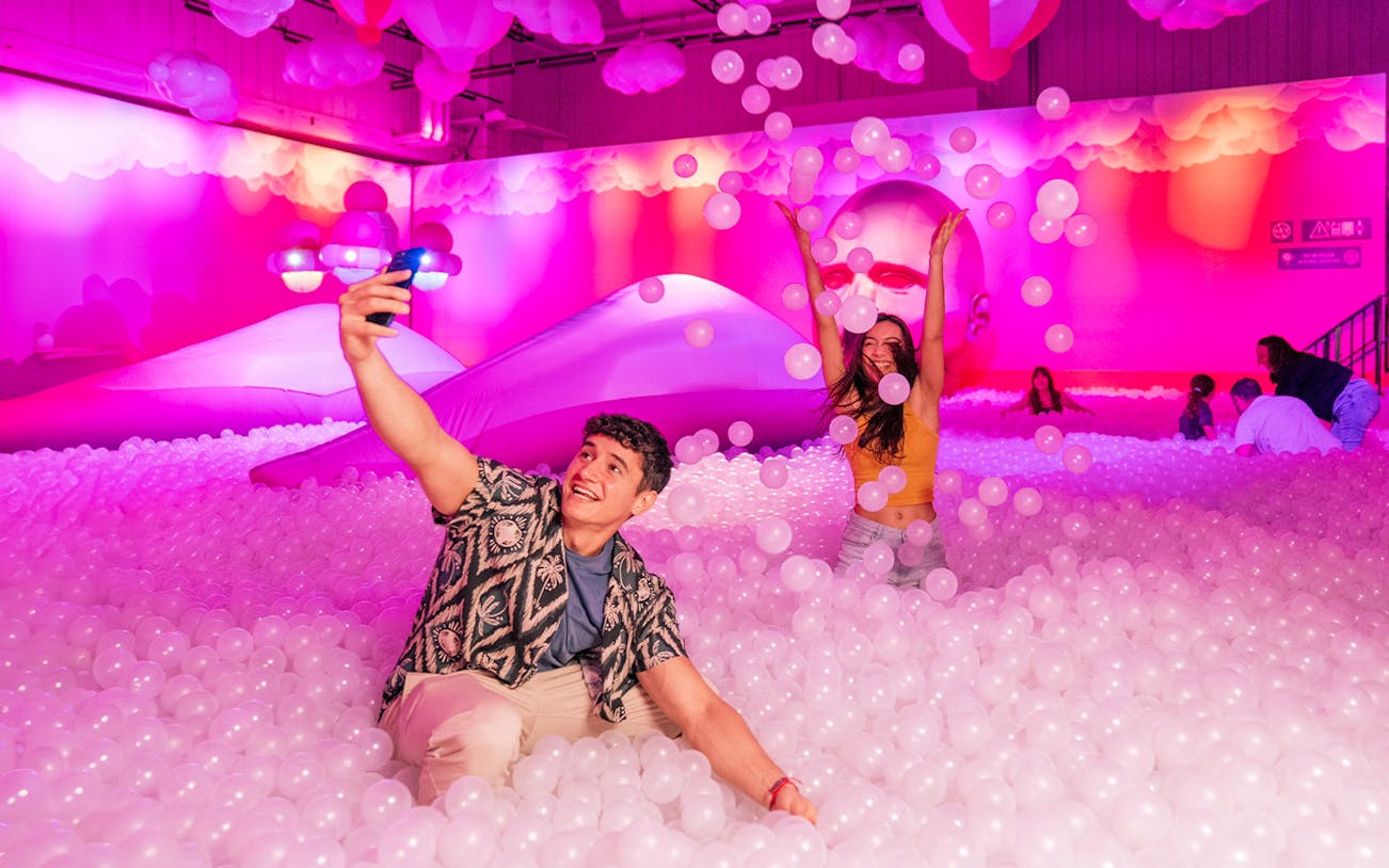 Visitors enjoying the Immersive Bubble Planet exhibit with colorful spheres in Singapore.