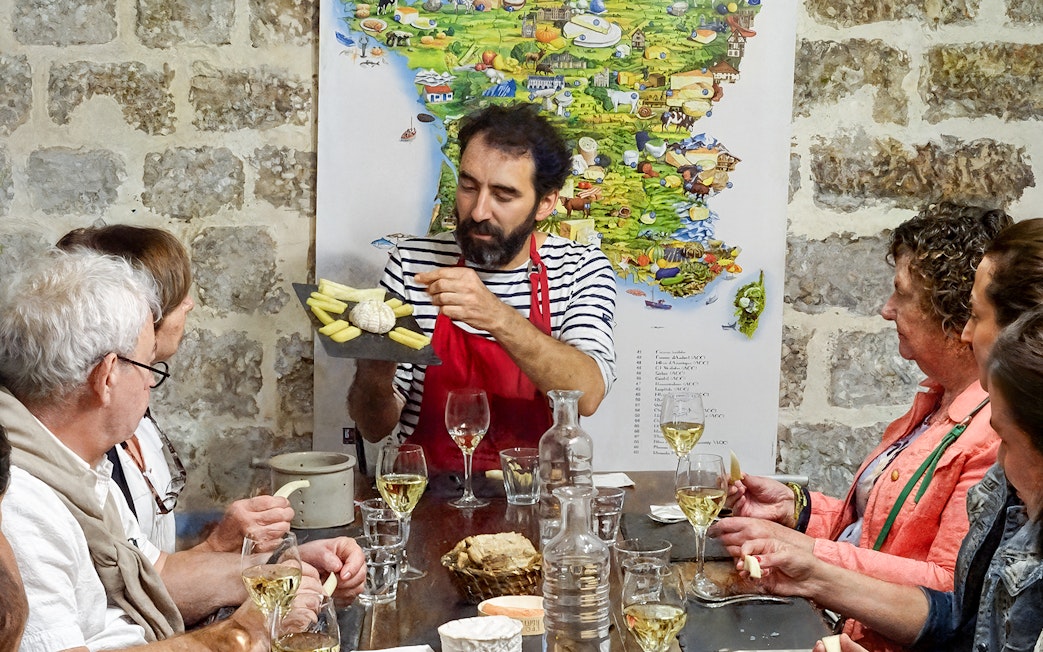 Expert discussing cheese varieties with visitors at the Cheese Museum in Paris, France.