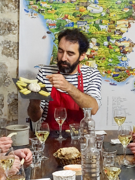 Expert discussing cheese varieties with visitors at the Cheese Museum in Paris, France.