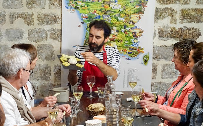 Expert discussing cheese varieties with visitors at the Cheese Museum in Paris, France.