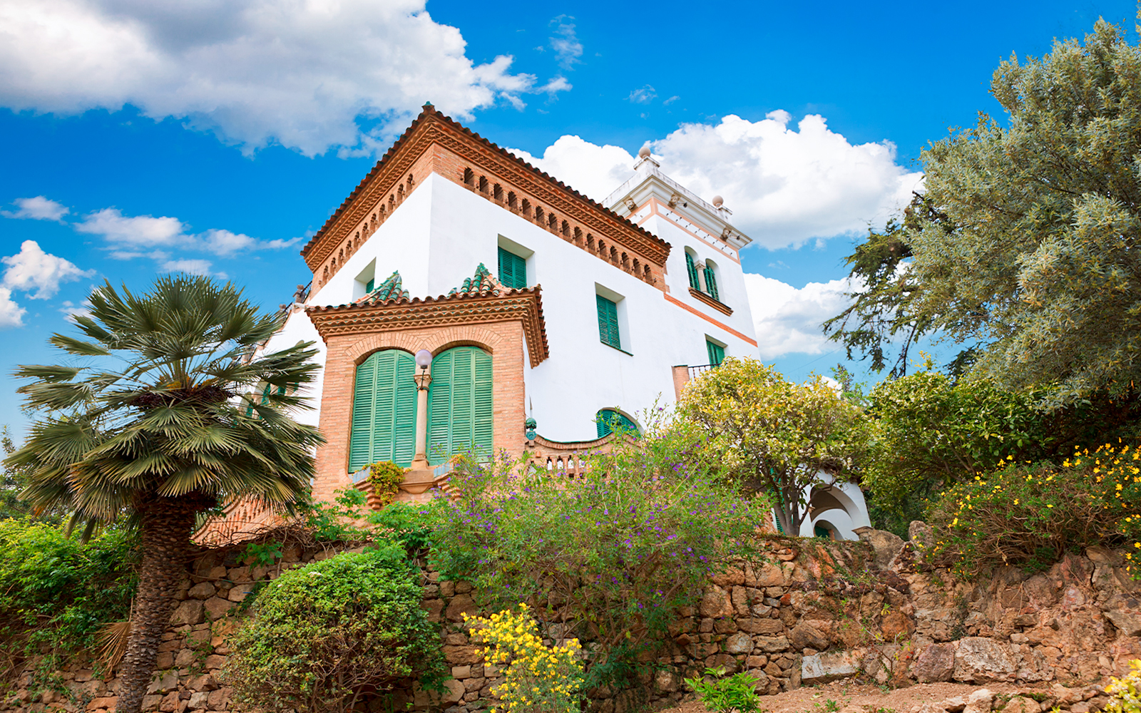 Casa Trias e Domenech in Park Guell, Barcelona, designed by Antoni Gaudi, surrounded by lush gardens.