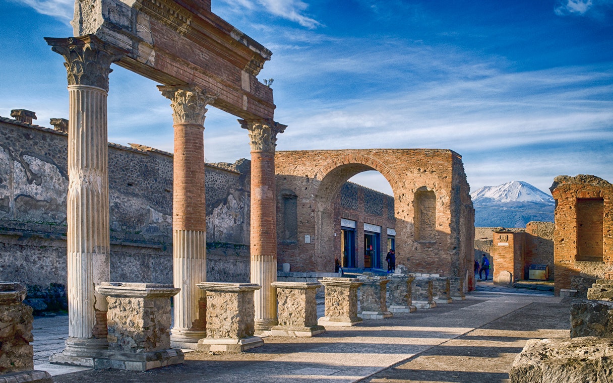 Ancient ruins of Pompeii with Mount Vesuvius in the background.