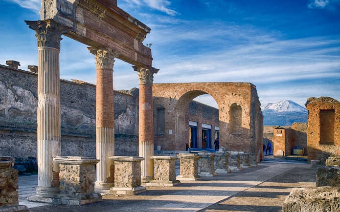 Ancient ruins of Pompeii with Mount Vesuvius in the background.