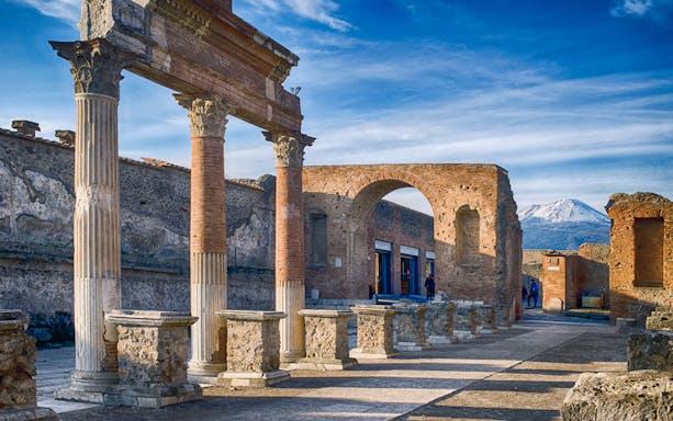 Ancient ruins of Pompeii with Mount Vesuvius in the background.